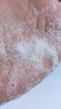 Rubbing palm gently. Close up view of hand full of soap foam. Cleansing bubbles, hand hygiene concept for daily skincare routine.