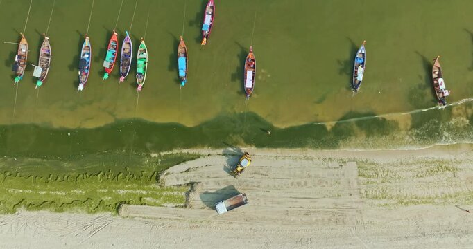Aerial perspective of Patong Beach in Phuket featuring green algae along the shore and a tractor performing beach maintenance. Ideal for themes of environment, tourism, and coastal management.