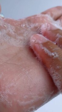 Gently rubbing soap on palm of hand. Close up view showing wet skin texture and delicate soap bubbles. Detailed demonstration of cleansing and skincare routine.