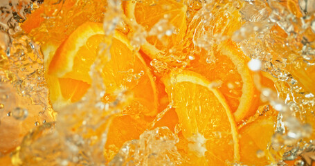 Fototapeta premium Fresh orange slices falling into sparkling water with bubbles and splashes. Vibrant citrus macro photo, perfect for beverage, freshness, summer, cocktail and healthy lifestyle visuals.