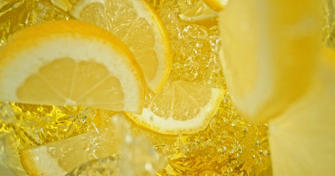Fresh lemon slices falling into sparkling water with bubbles and splashes. Bright yellow citrus macro photo, perfect for beverage, freshness, summer, cocktail and healthy lifestyle visuals.