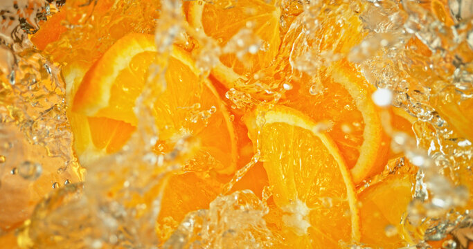 Fresh orange slices falling into sparkling water with bubbles and splashes. Vibrant citrus macro photo, perfect for beverage, freshness, summer, cocktail and healthy lifestyle visuals.