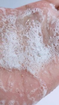 Close up of palm covered in soap bubble foam. Hand hygiene, cleansing bubbles, white lather for daily skincare routine.