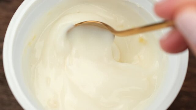 Fruit Yogurt stirred with Spoon. Eating mango or peach fruit yogurt
