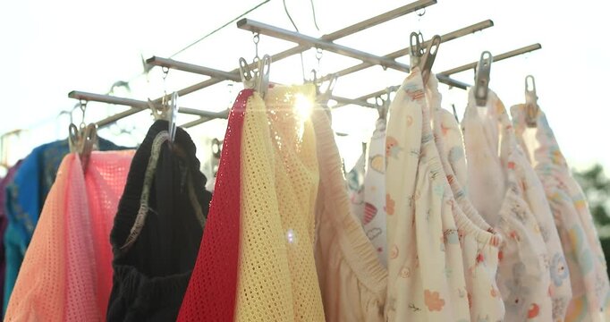 Baby clothes and fabric hanging in warm sunlight outdoors, capturing freshness, cleanliness, cozy family lifestyle, and natural morning light