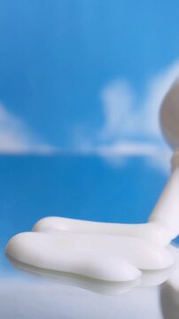Applying white cream in even zigzag pattern on reflective glass surface. Close up view with blurred blue cloudy background. Freshness and UV protection skincare concept.