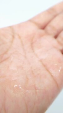 Shiny palm with clear liquid on hand. Skin cleansing soap liquid. Close up view. Transparent texture for daily hygiene and skincare.