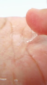 Showing thick clear liquid on palm surface. Close up view. Transparent viscous fluid, skincare or cosmetic texture concept on white background.