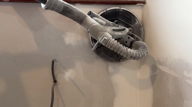 Wall repair work. Sander in action, medium shot. A construction worker sands drywall and putty. Home renovation and restoration.