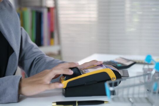 Female hand puts bankcard into reader on defocused background. Payment with credit card. EDC machine or credit card terminal for cashless payments. Electronic finance and shopping concept
