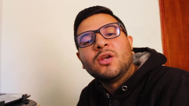 A young Latino man is speaking to the camera against a white background inside his home in Bosa, Bogota, Colombia. Concept of UGC and digital content