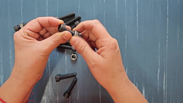 A person is demonstrating how to put a nut on a black Allen screw.