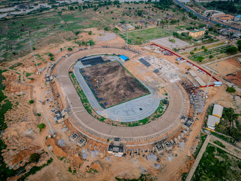 Kaduna, Nigeria - 13 May 2026: Aerial view of Ahmadu Bello Stadium under renovation with concrete stands, floodlights, and a dirt pitch surrounded by the city landscape.