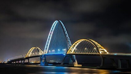 Fototapeta premium Illuminated Arched Bridge at Night with Blue and Yellow Lights Reflecting on Water
