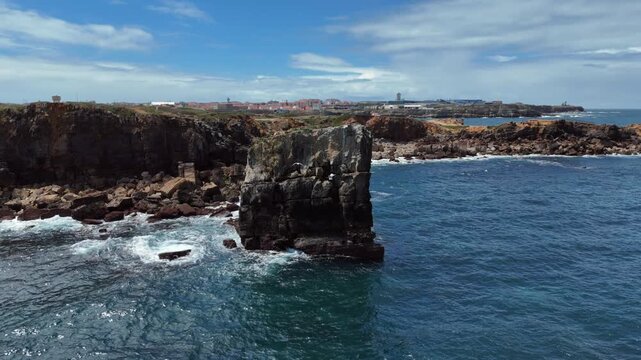 Aerial View of Isolated Sea Stack and Dramatic Coastal Cliffs With Seaside Town and Seagull in Background