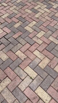 red brick pavement. Herringbone brick sidewalk pattern of pavement tiles on rainy day background texture. Wet sidewalk pathway surface. Exterior design element. Geometric diagonal zigzag tile pattern.