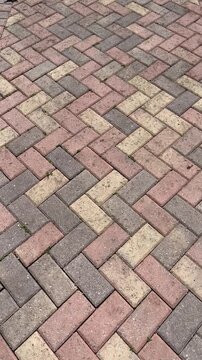 red brick pavement with zigzag pattern. Herringbone brick sidewalk pattern of pavement tiles on rainy day background texture. Wet sidewalk pathway surface. Patio pavement. Exterior design element.