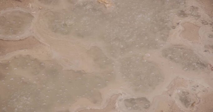 Volcanic pit with mud and boiling water with steam rising to the surface in a pond at Furnas, Azores.