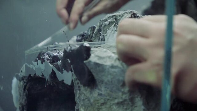 Hands Gluing Rocks for Miniature Landscape Model