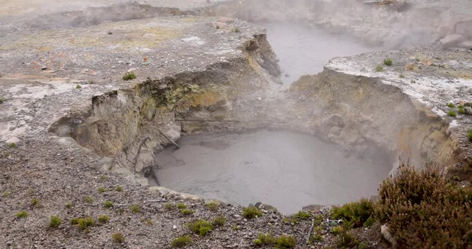 Volcanic pit with mud and boiling water with steam rising to the surface in a pond at Furnas, Azores.