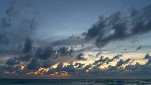 Time lapse view of dramatic clouds above the sea during twilight, capturing motion, mood, and changing light over the coastline. turbulent cloud formations and gentle surf, perfect for weather