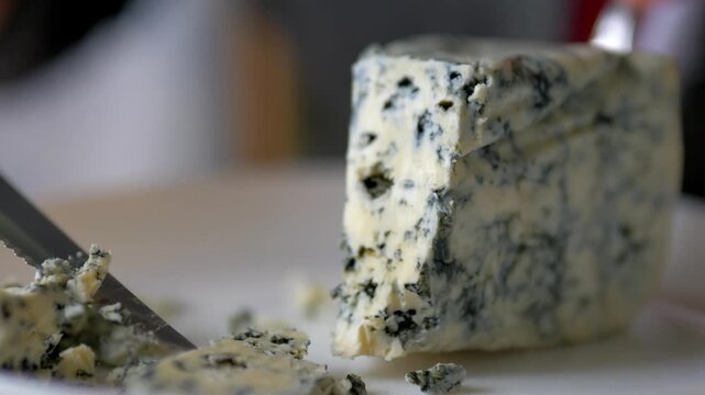 Slicing Premium Blue Cheese with Serrated Knife &mdash; Gourmet Roquefort or Stilton Texture Close-up