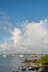 Fototapeta premium Sailboats in harbor with dramatic clouds and rainbow in sky on sunny day in Sarasota Florida.