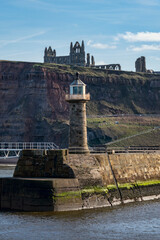 Fototapeta premium whitby abbey on the cliff top above the east pier lighthouse sunny day low sun no people