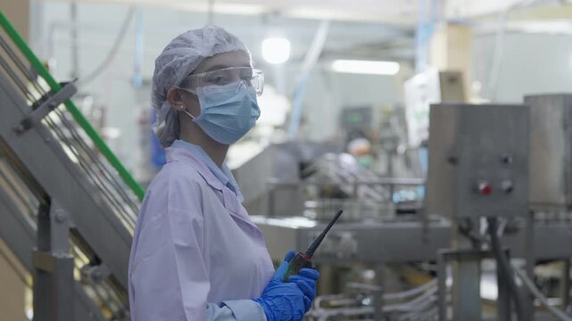 Food factory automated production line, Food factory worker in safety mask, gloves, gown, hairnet, hygiene and production line inspecting industrial machine in cleanroom industry