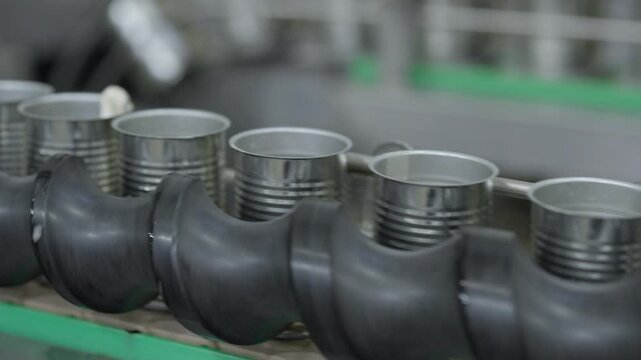 Food factory automated production line, industrial conveyor line with metal cans and black rubber rollers manufacturing plant, metal container rubber tube industrial conveyor manufacturing line