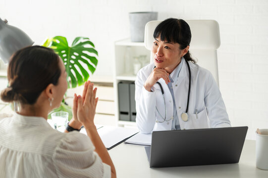 Female physician talking with patient during healthcare consultation in modern office. Medical advice, emotional support and preventive care concept.