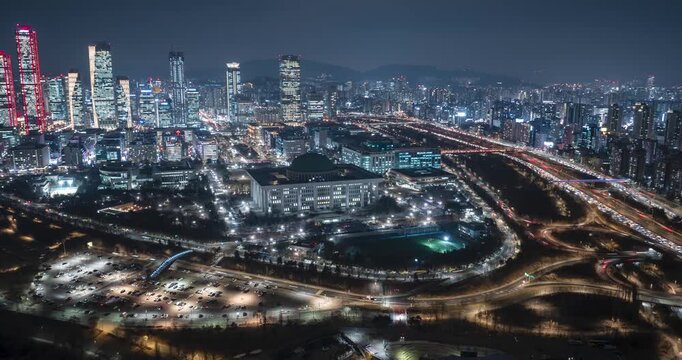 Night hyperlapse of Yeouido skyline and National Assembly with vibrant light trails from city traffic.
