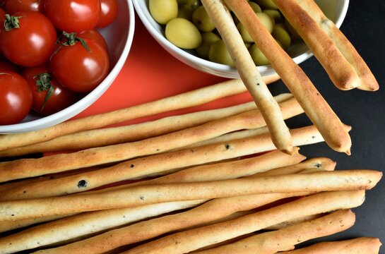 Olive bread sticks, cherry tomatoes and olives in the background