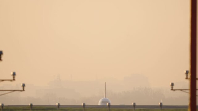 Front view passenger aircraft departure in early morning conditions, telephoto close up with runway lights and golden sunrise mist, clean atmospheric aviation takeoff sequence