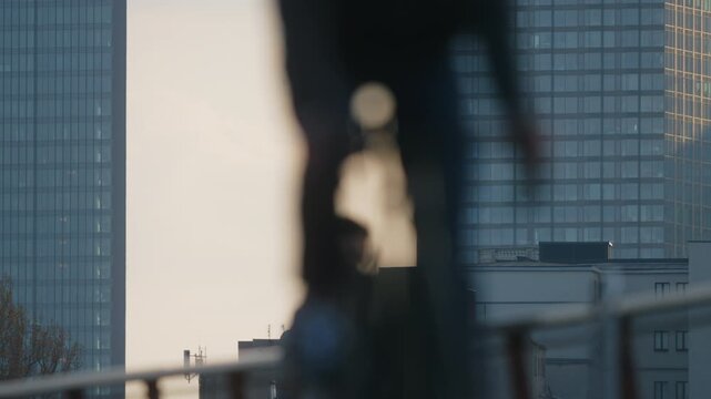 Soft light urban telephoto shot with blue glass skyscrapers skyline in focus, shallow depth of field separating moving pedestrians in foreground, calm everyday city rhythm