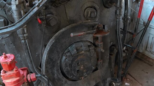 The interior cab of a vintage antique French era steam locomotive, focusing on the backhead of the boiler. The large circular firedoor in the center, used for loading coal into the firebox
