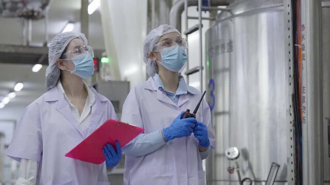 Food factory automated production line, Laboratory technician protective gear inspecting industrial tank factory, teamwork and quality control sterile processing environment with safety mask, glove