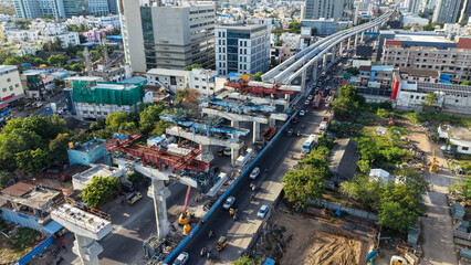 Aerial view of metro rail construction over busy city road with elevated track and urban buildings showing infrastructure development and public transport expansion © VisualTreat12