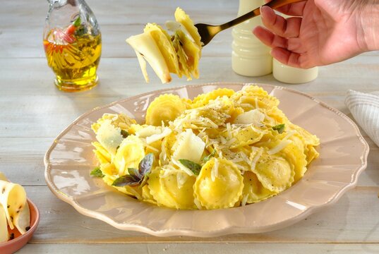 Delight in the sight of perfectly cooked ravioli layered with fresh herbs and cheese, ready to be enjoyed. The inviting kitchen exudes warmth, highlighting a moment of culinary joy