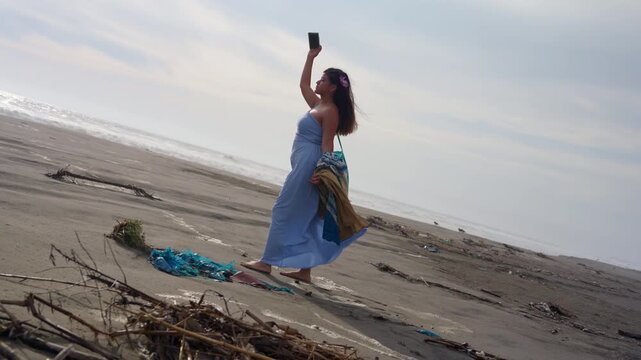 Young woman taking selfies on a polluted sandy beach