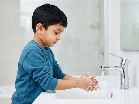 indian boy washing hands at bathroom sink for child hygiene infection prevention and healthy habits concept