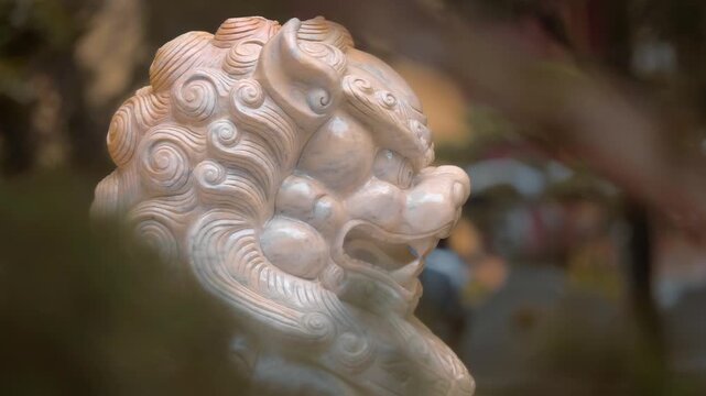 A close-up of a carved stone statue, a Chinese guardian snow lion also known as a Foo Dog made from white marble that is standing in the temple garden of the Truc Lam Zen Monastery in Da Lat, Vietnam
