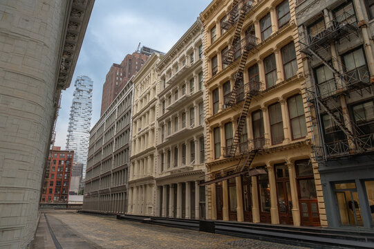 New york, usa august 18,2024. Cobblestone street in manhattan's tribeca district showcasing typical historic cast iron architecture with a modern skyscraper in background