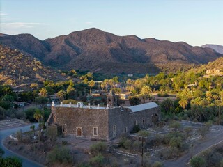 Fototapeta premium Sunrise light reveals the Mission of Santa Rosalia in Mulege, with mountains and oasis visible nearby in Baja California Sur, Mexico