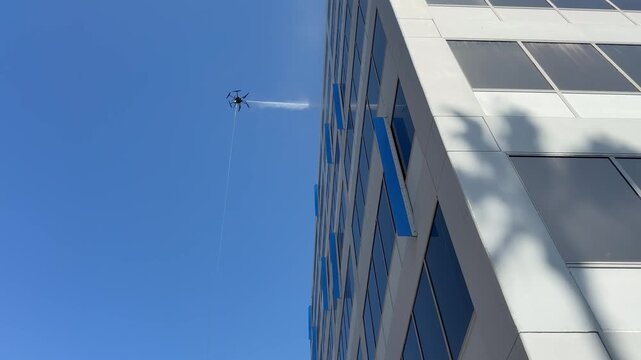 Drone washing windows on building
