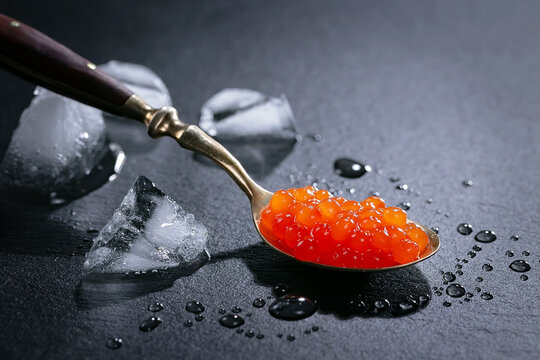 Red caviar, a healthy and tasty seafood product, in a spoon, on a dark background.