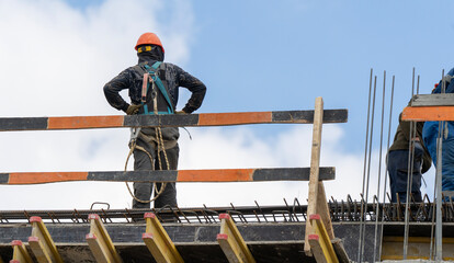 Worker stands atop steel frame, wearing hard hat and safety gear © I