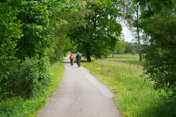 Obraz premium Scenic rural landscape with country road and senior cycling couple at Swiss city of Zürich district Affoltern on a cloudy spring day. Photo taken May 15th, 2026, Zurich Affoltern, Switzerland.