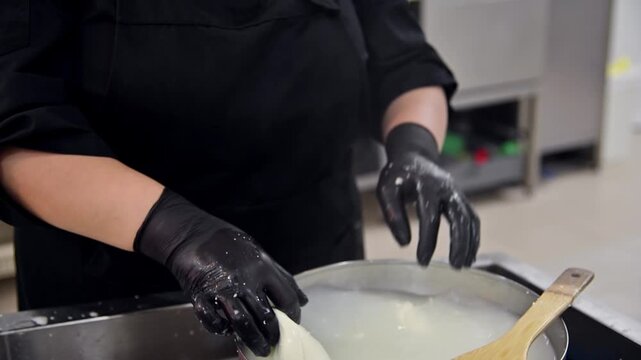 Woman stretches fresh cheese curds in kitchen, showcasing stracciatella production