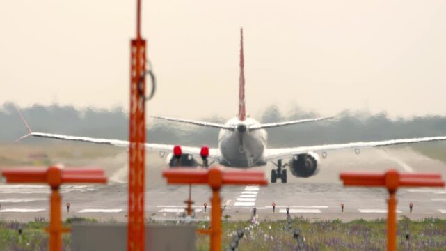 Rear view of jet aircraft accelerating along runway during takeoff roll at airport.